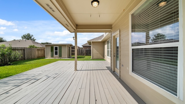 wooden terrace with a storage shed and a lawn