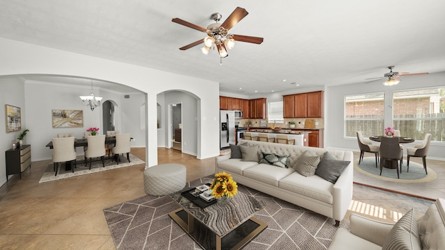 living room featuring ceiling fan with notable chandelier, light tile patterned floors, and crown molding