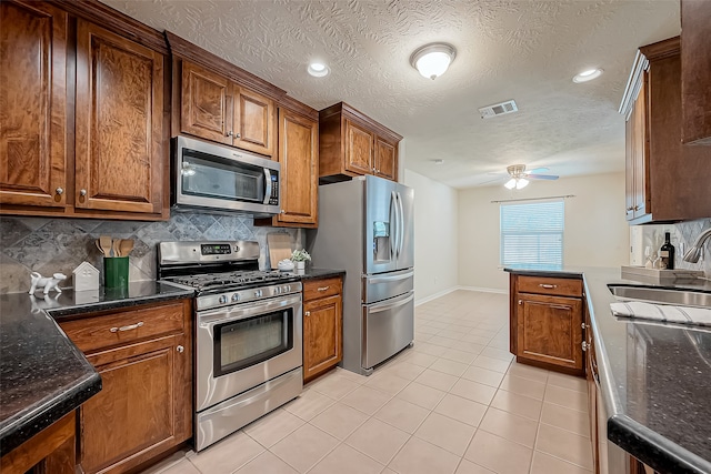 kitchen with decorative backsplash, a textured ceiling, sink, ceiling fan, and appliances with stainless steel finishes