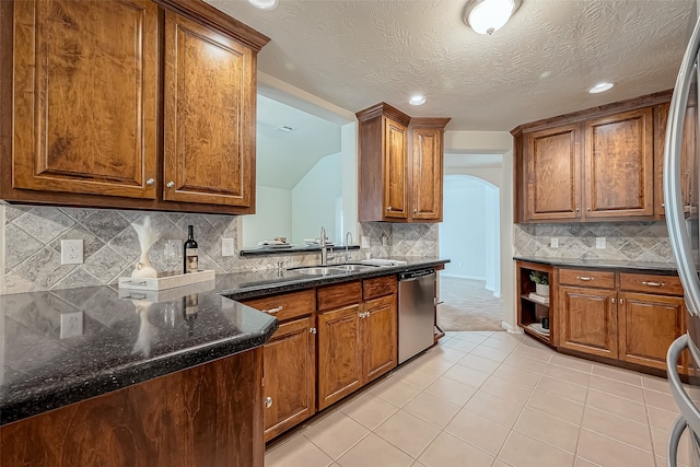 kitchen with a textured ceiling, appliances with stainless steel finishes, sink, and backsplash