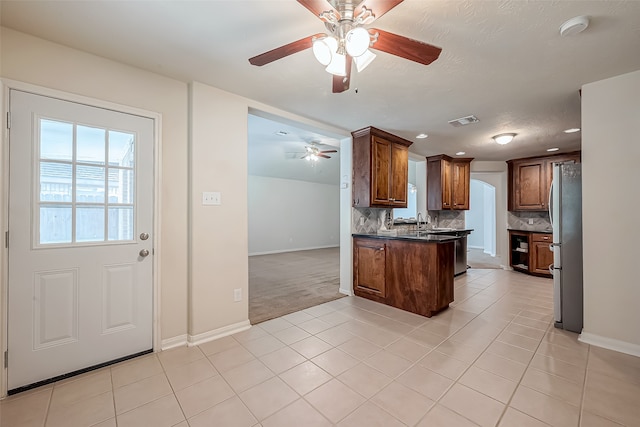 kitchen featuring tasteful backsplash, stainless steel refrigerator, light tile patterned floors, kitchen peninsula, and ceiling fan