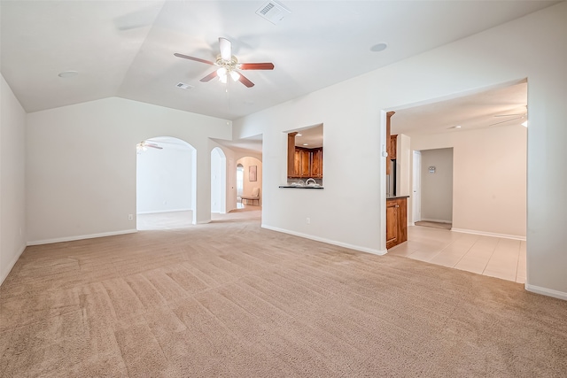 unfurnished living room with vaulted ceiling, light colored carpet, and ceiling fan