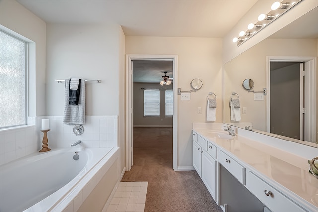 bathroom featuring vanity, a healthy amount of sunlight, and a relaxing tiled tub