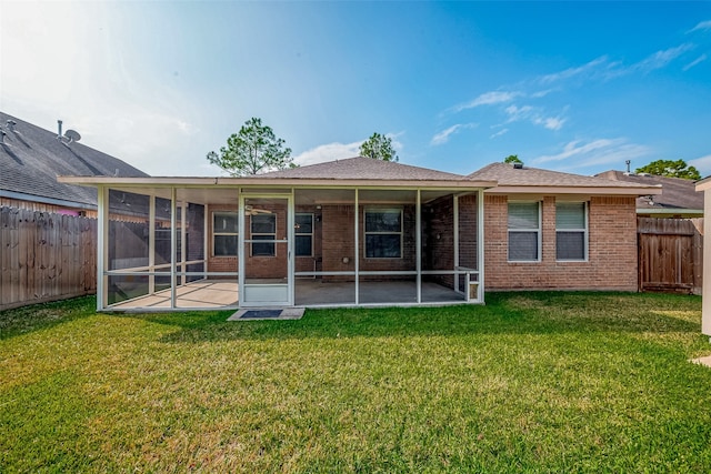 rear view of property featuring a lawn, a sunroom, and a patio area