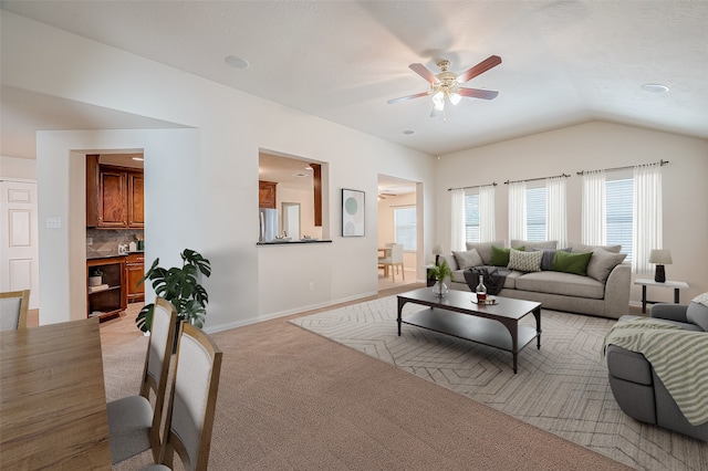 carpeted living room with ceiling fan and vaulted ceiling