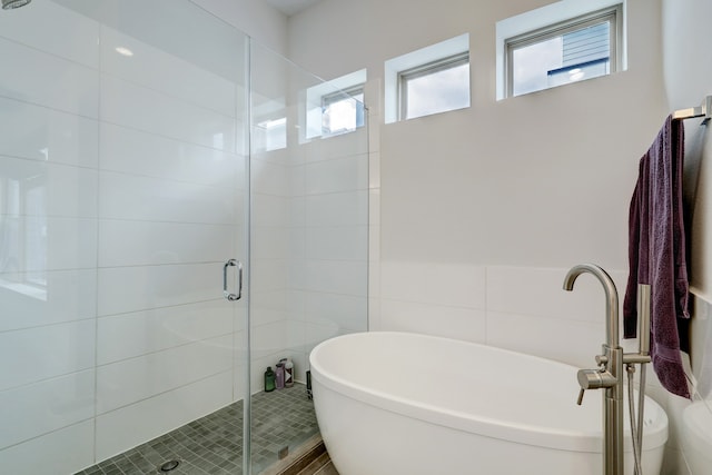 bathroom with shower with separate bathtub and tile walls