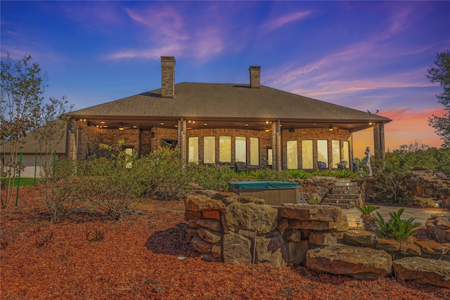 back house at dusk featuring a hot tub and ceiling fan