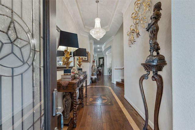 foyer with dark wood-type flooring, a chandelier, and ornamental molding