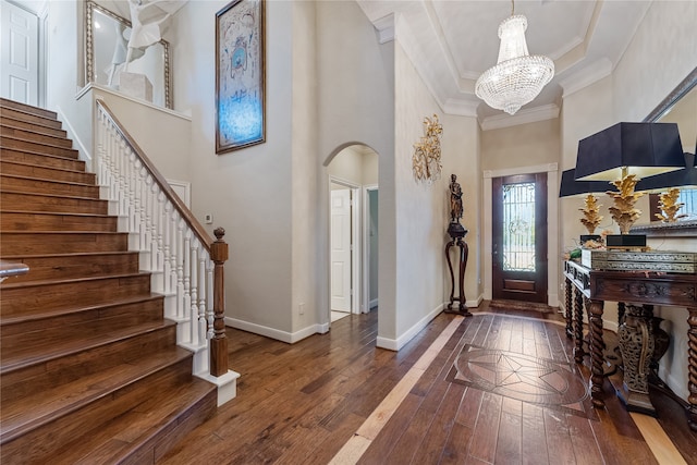 foyer featuring a high ceiling, wood-type flooring, a notable chandelier, and ornamental molding