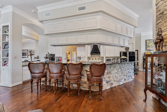 bar featuring white cabinets, crown molding, custom exhaust hood, and dark hardwood / wood-style flooring