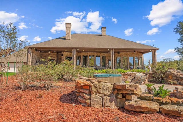 rear view of house with a hot tub and ceiling fan