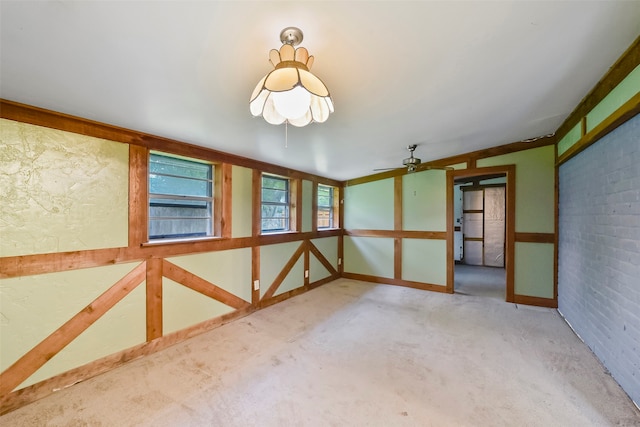 carpeted empty room featuring brick wall