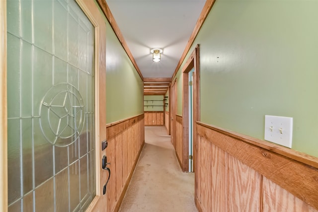 hallway with wooden walls, light carpet, and crown molding