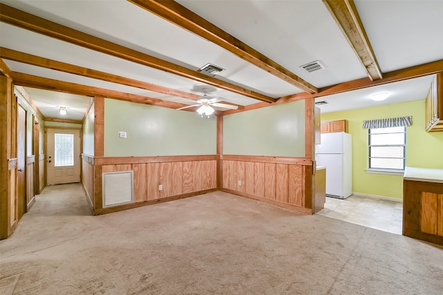 spare room featuring a wealth of natural light, ceiling fan, beam ceiling, and light carpet