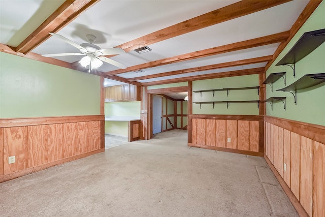 spare room with beamed ceiling, wooden walls, light colored carpet, and ceiling fan