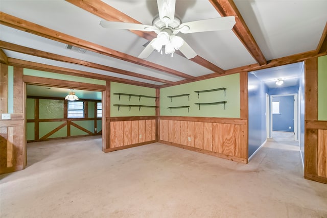 interior space with light colored carpet, wooden walls, and ceiling fan