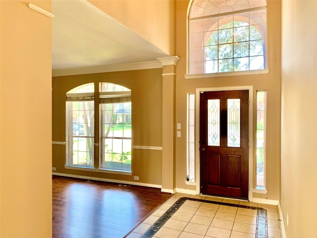 entrance foyer with ornamental molding, wood-type flooring, a high ceiling, and decorative columns