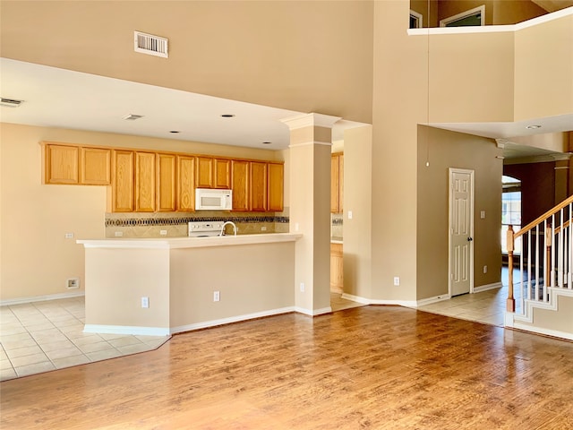 kitchen with light hardwood / wood-style flooring, white appliances, and a towering ceiling