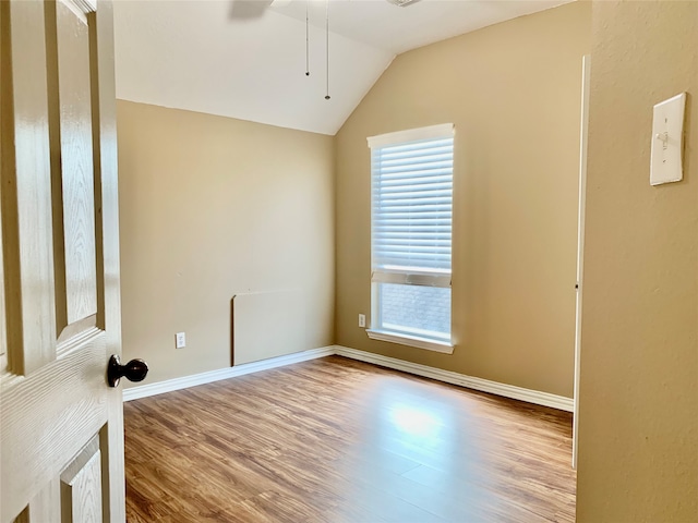 spare room featuring light wood-type flooring, lofted ceiling, and ceiling fan