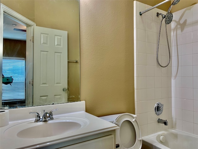 full bathroom featuring vanity, tiled shower / bath combo, and toilet