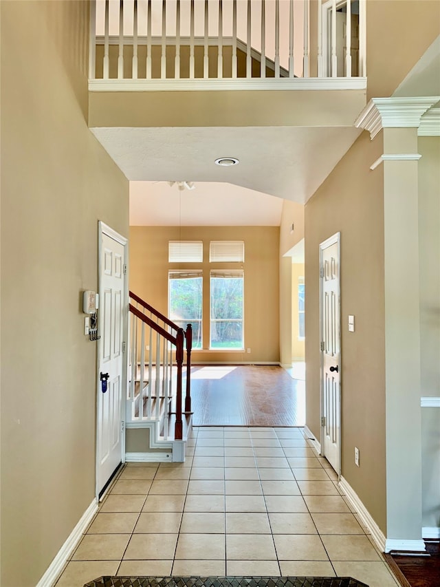 foyer with a towering ceiling, ornate columns, and light hardwood / wood-style floors