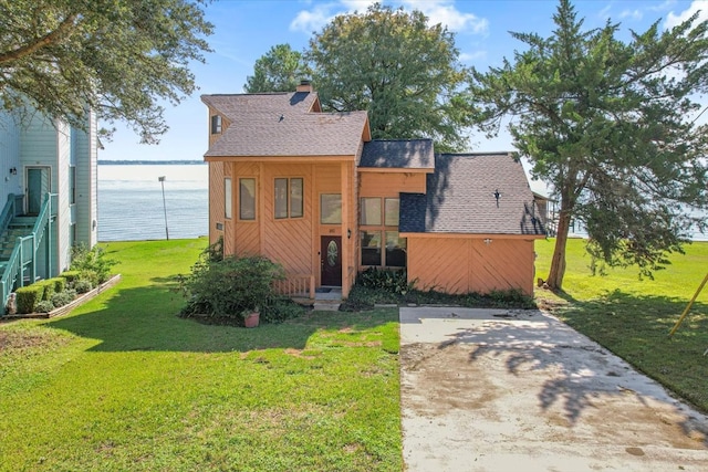 view of front of property with a patio area, a water view, and a front lawn