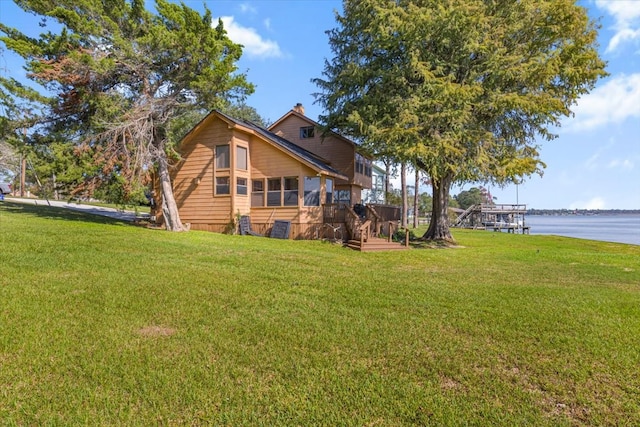 rear view of property with a yard and a deck with water view