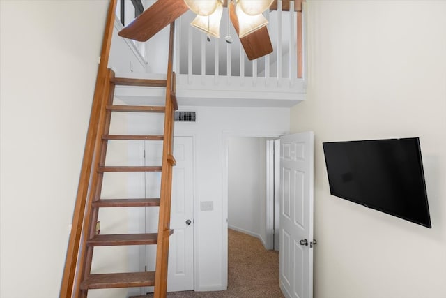 stairway with carpet flooring and ceiling fan