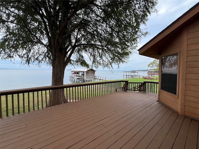 wooden deck with a water view and a lawn