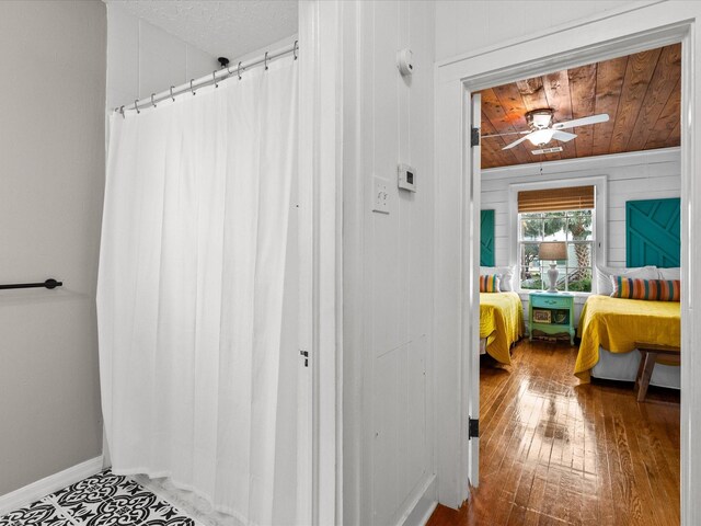 bathroom with hardwood / wood-style flooring, wood walls, and ceiling fan