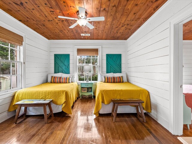 bedroom with wood walls, hardwood / wood-style flooring, ceiling fan, and wood ceiling