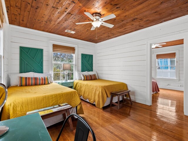 bedroom with ceiling fan, wood-type flooring, wood walls, and wood ceiling