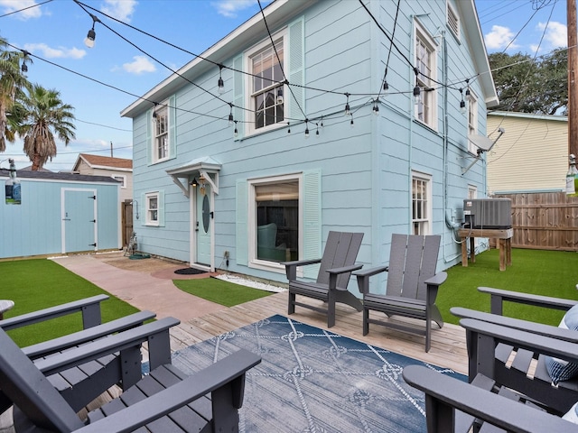 rear view of property with a deck, a yard, central AC, and a storage unit