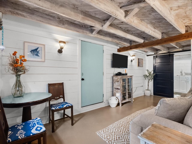 living room featuring wood walls, concrete flooring, and a barn door