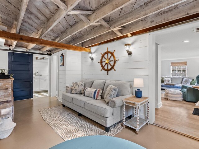 living room featuring beamed ceiling, a barn door, wooden walls, and wooden ceiling