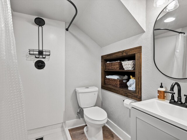 bathroom featuring hardwood / wood-style floors, toilet, vanity, and vaulted ceiling