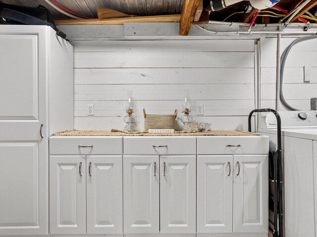 clothes washing area featuring washer / dryer, wooden walls, and cabinets