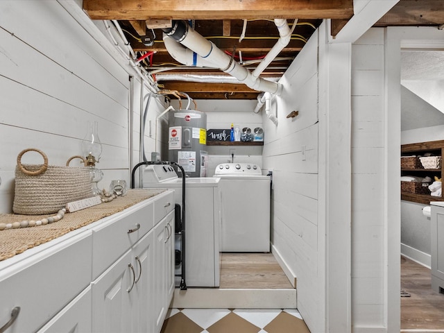 laundry room with wood walls, separate washer and dryer, cabinets, and electric water heater