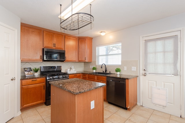 kitchen featuring sink, black appliances, dark stone counters, a kitchen island, and decorative backsplash