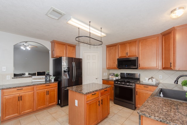 kitchen with appliances with stainless steel finishes, light tile patterned floors, sink, ceiling fan, and a center island