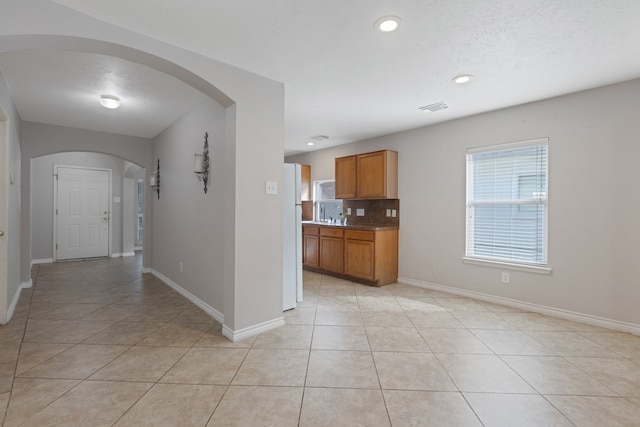 kitchen featuring light tile patterned flooring, white fridge, and tasteful backsplash