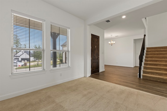 spare room featuring a chandelier, wood-type flooring, and a healthy amount of sunlight