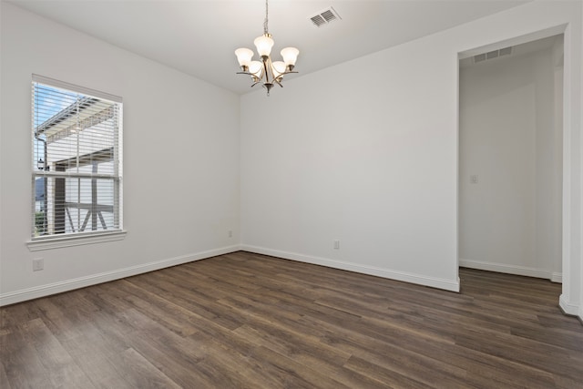 spare room featuring dark hardwood / wood-style floors and an inviting chandelier