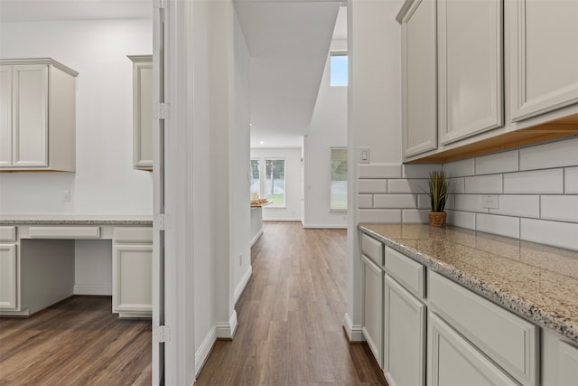 interior space with tasteful backsplash, light stone counters, and dark hardwood / wood-style floors