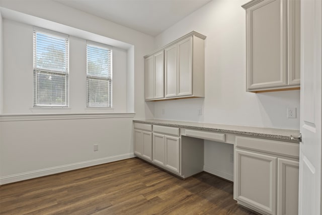 unfurnished office with dark hardwood / wood-style flooring and built in desk