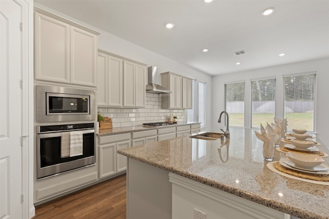 kitchen with sink, wall chimney exhaust hood, a healthy amount of sunlight, light hardwood / wood-style flooring, and appliances with stainless steel finishes