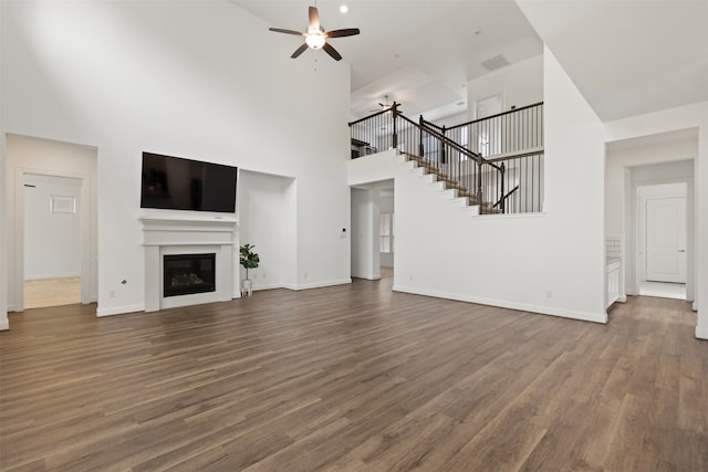 unfurnished living room with a high ceiling, dark hardwood / wood-style flooring, and ceiling fan