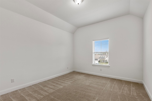 carpeted spare room with vaulted ceiling