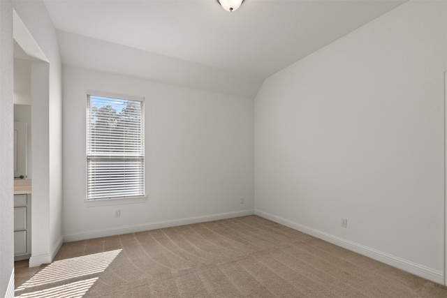 unfurnished room with light colored carpet and lofted ceiling