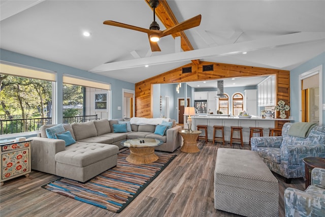 living room featuring dark hardwood / wood-style flooring, wood walls, ceiling fan, and vaulted ceiling with beams